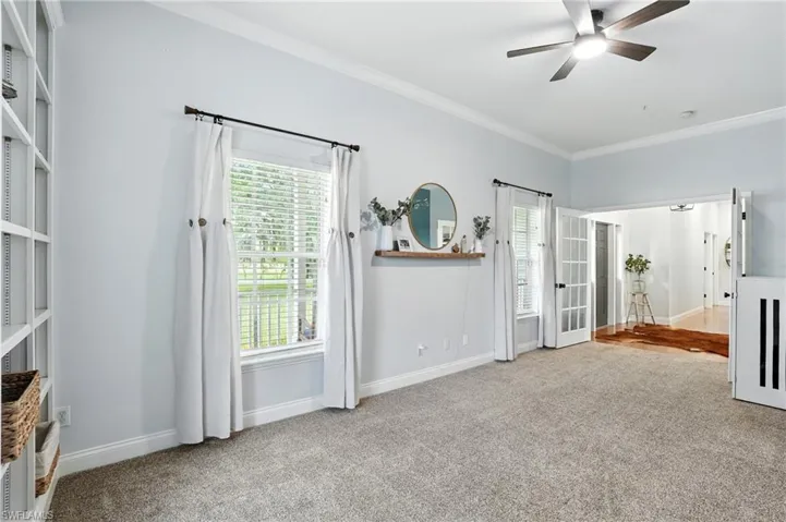 Unfurnished bedroom featuring ornamental molding, light colored carpet, french doors, and ceiling fan
