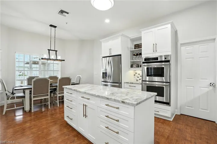 Kitchen featuring open shelves, white cabinets, stainless steel appliances, light stone counters, and hanging light fixtures