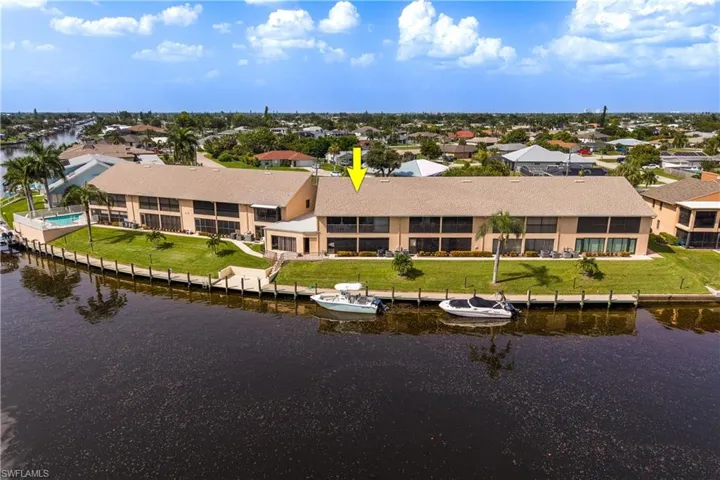 Waterfront multi-unit property featuring a private dock, communal swimming pool, screened balconies, and a manicured lawn