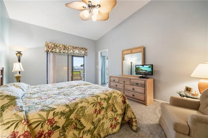 Bedroom featuring vaulted ceilings, carpeted flooring, and a glass sliding door opening to a private balcony