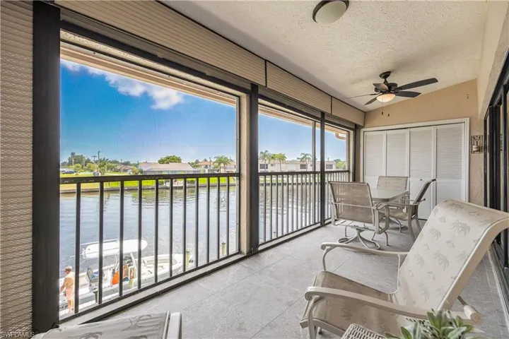 Screened outdoor living area featuring a waterway, black iron railing, beige ceiling, ceiling fan, and sliding closet doors