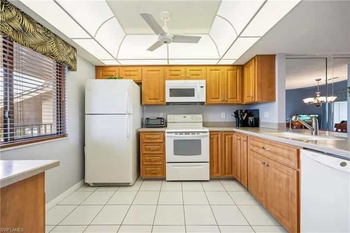 Kitchen featuring wood-finish cabinetry, white appliances, and a composite countertop