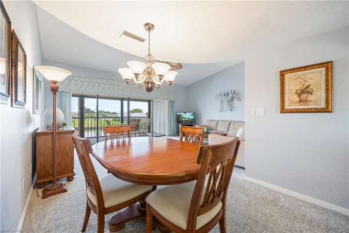Dining area featuring a classic wood-finish table and chairs, a multi-light chandelier, and light-toned carpeting