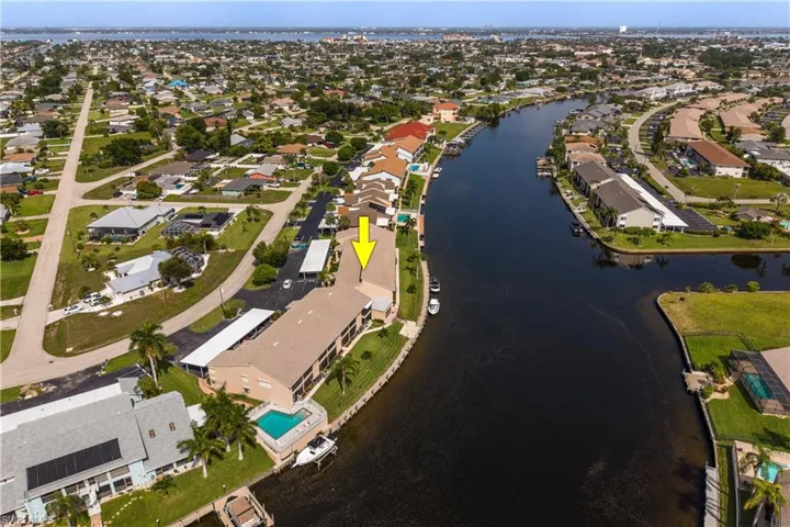 Multi-story building featuring a waterside swimming pool, private boat docks, and covered parking structures