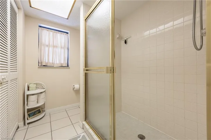 Shower enclosure with a framed glass door, white square tile walls, and a matching tiled floor