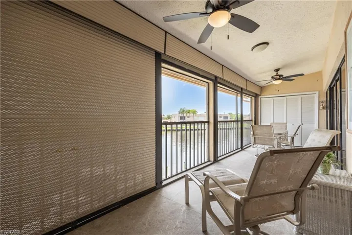 Screened patio featuring water views, tile flooring, two ceiling fans, and a storage closet with bi-fold doors
