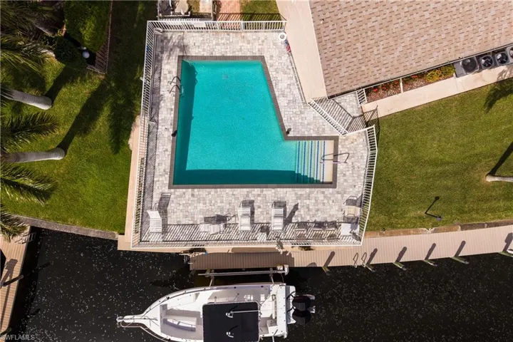 Geometric swimming pool with paver decking and white perimeter fencing