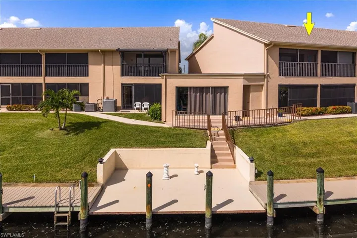 Waterfront property featuring a private boat dock, concrete seawall, and a terraced backyard leading to the residence
