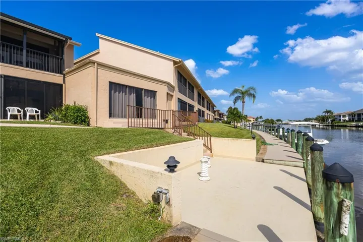 Waterfront property featuring a private patio, sloped grassy area, and a deep water canal