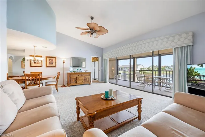 Spacious living area featuring vaulted ceilings and light-colored carpeting