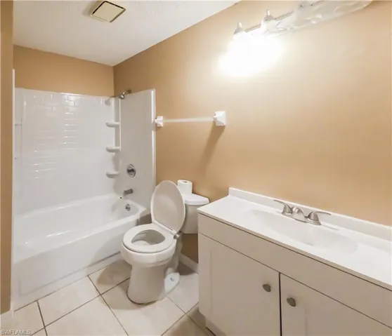 Full bathroom featuring shower / bathtub combination, vanity, light tile patterned floors, and a textured ceiling