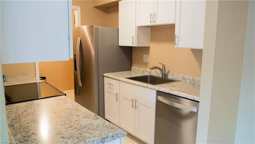 Kitchen with stainless steel dishwasher, white cabinets, and electric range