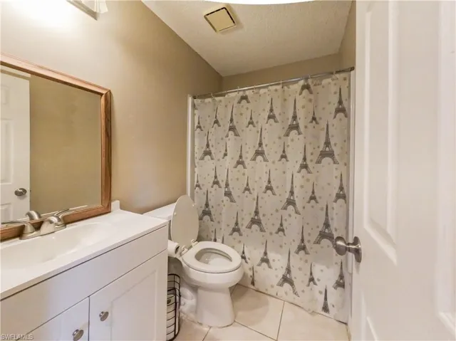 Full bath featuring curtained shower, vanity, light tile patterned floors, and a textured ceiling