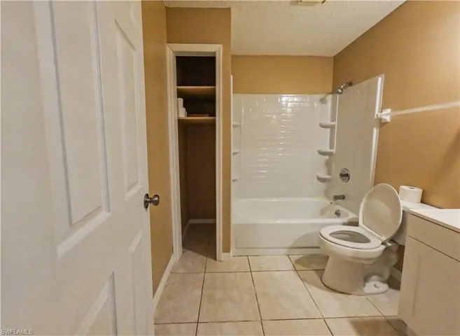 Full bathroom featuring vanity, shower / bath combination, a textured ceiling, and light tile patterned floors