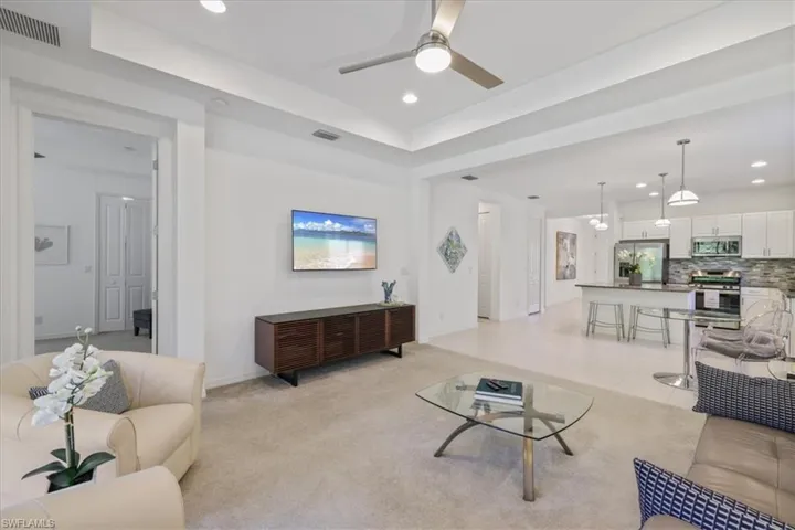 Living room featuring a ceiling fan, recessed lighting, light carpet, and light tile patterned floors