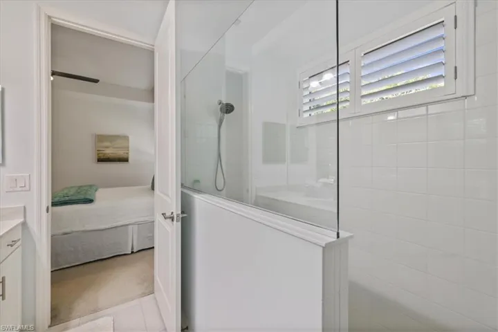 Bathroom featuring a walk in shower, ensuite bath, vanity, and light carpet