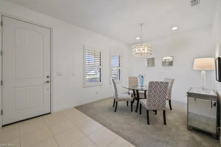 Dining room featuring light tile patterned flooring, hanging lights, and light carpet