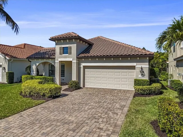 Mediterranean / spanish house with stucco siding, driveway, a garage, a front lawn, and a tile roof