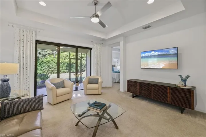 Living area featuring a raised ceiling, ceiling fan, carpet, and recessed lighting