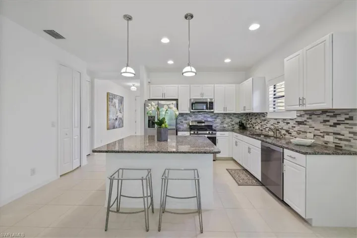Kitchen with dark stone countertops, stainless steel appliances, and white cabinets