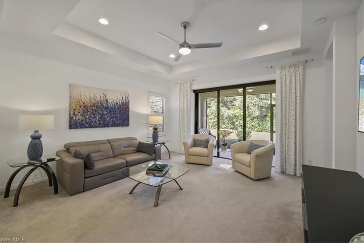 Carpeted living area featuring ceiling fan, a tray ceiling, and recessed lighting