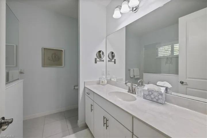 Full bath with vanity, light tile patterned flooring, and suspended lighting