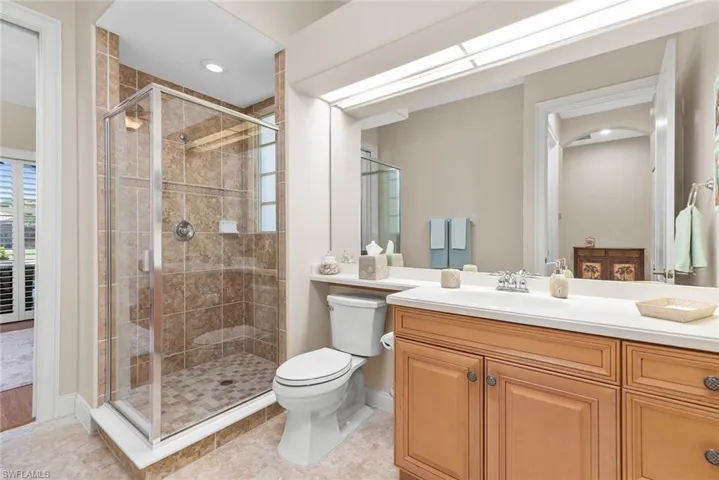 Bathroom with tile patterned flooring, vanity, toilet, and a shower with door