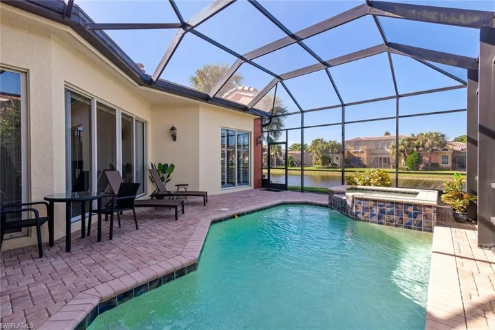 View of pool featuring a lanai, an in ground hot tub, a water view, and a patio area