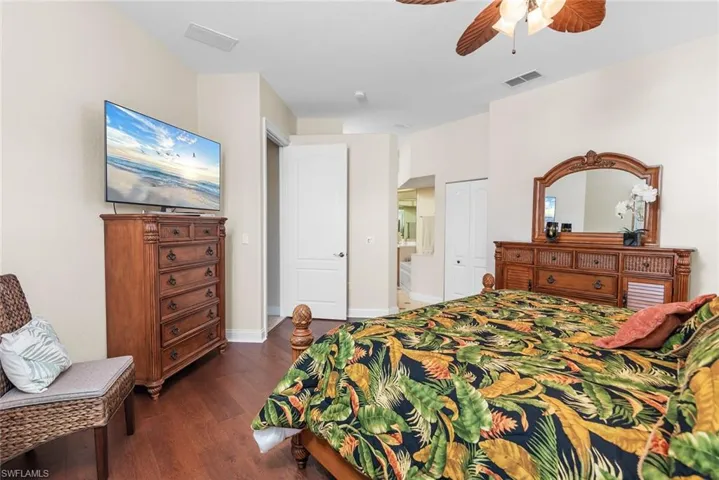 Bedroom with ceiling fan, dark hardwood / wood-style floors, and a closet