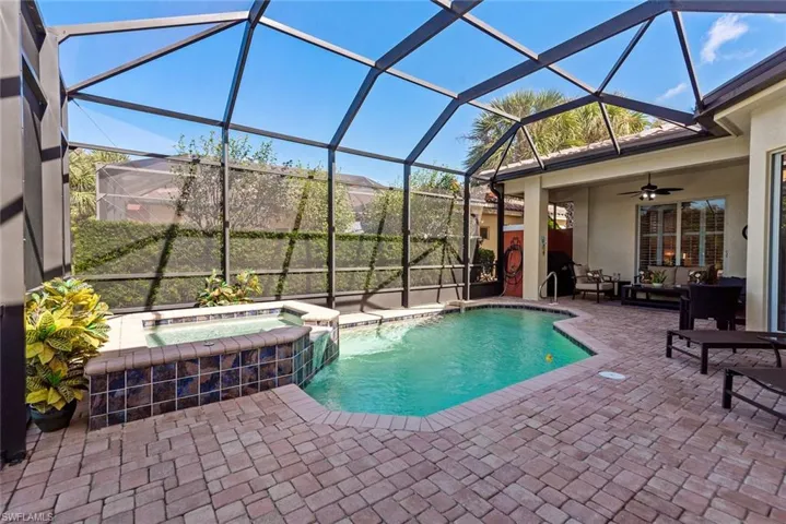 View of swimming pool featuring a patio, a lanai, ceiling fan, and an in ground hot tub