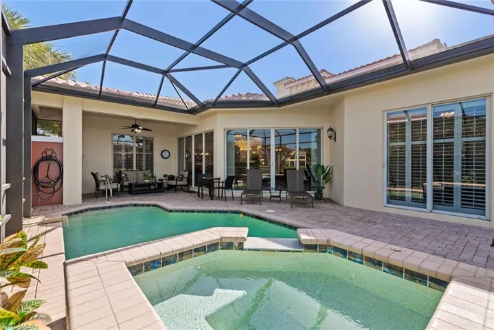 View of swimming pool featuring ceiling fan, a patio, a lanai, and an in ground hot tub