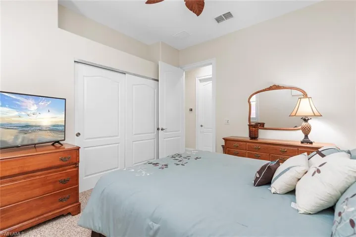 Carpeted bedroom with ceiling fan and a closet