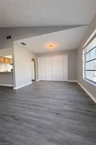 Unfurnished living room featuring arched walkways and dark wood finished floors