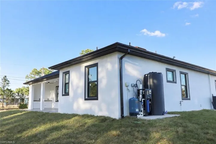 View of side of home featuring a lawn, stucco siding, and a patio area