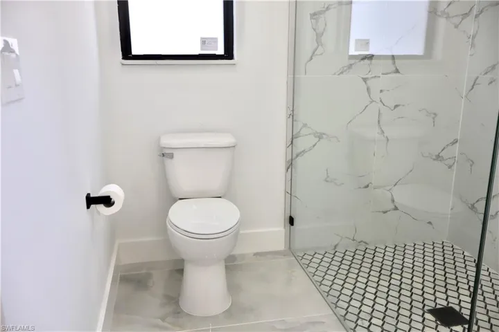 Full bath featuring a marble finish shower and toilet
