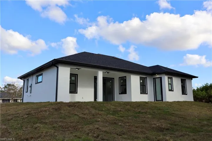 Back of house featuring a lawn, stucco siding, and a patio area