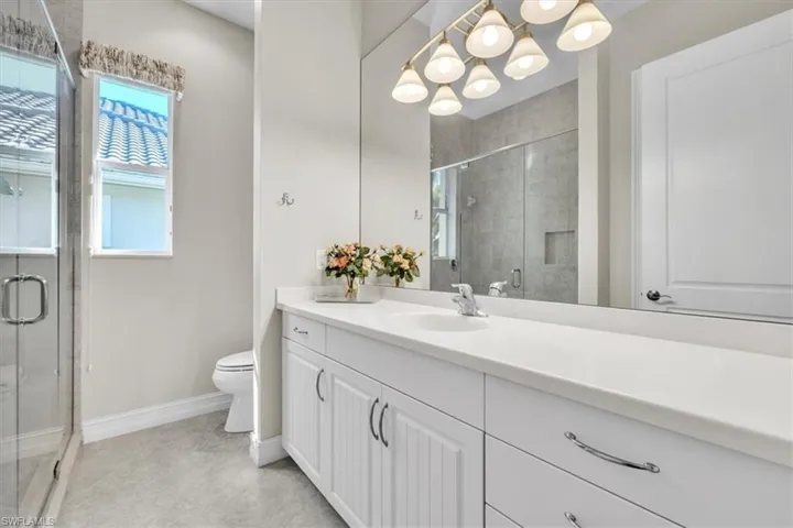 Bathroom featuring a shower stall, vanity, and a chandelier