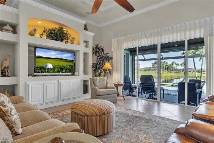 Tiled living area featuring built in shelves, a ceiling fan, and ornamental molding