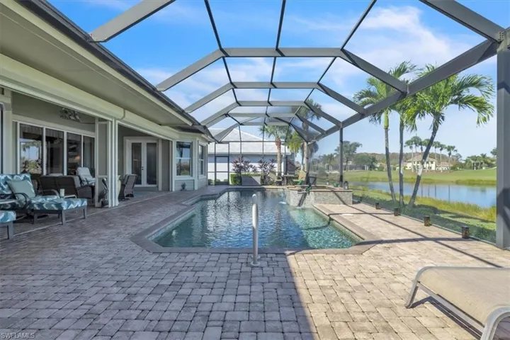 View of swimming pool featuring a sunroom, a patio, a lanai, a pool with connected hot tub, and a water view