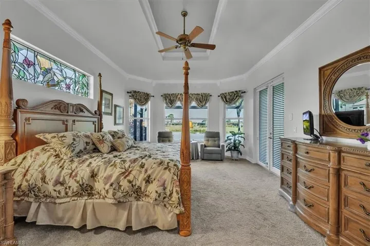 Bedroom with light colored carpet, a ceiling fan, and ornamental molding