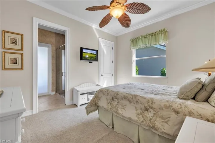 Bedroom with light carpet, ceiling fan, and ornamental molding
