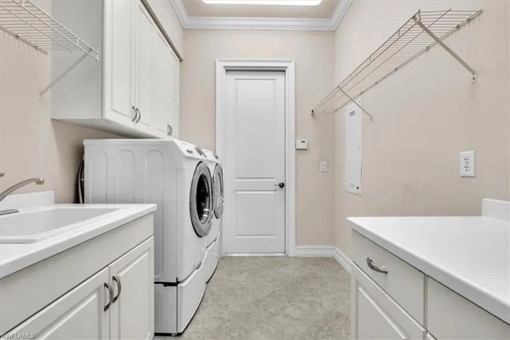 Washroom with cabinet space, crown molding, independent washer and dryer, and electric panel