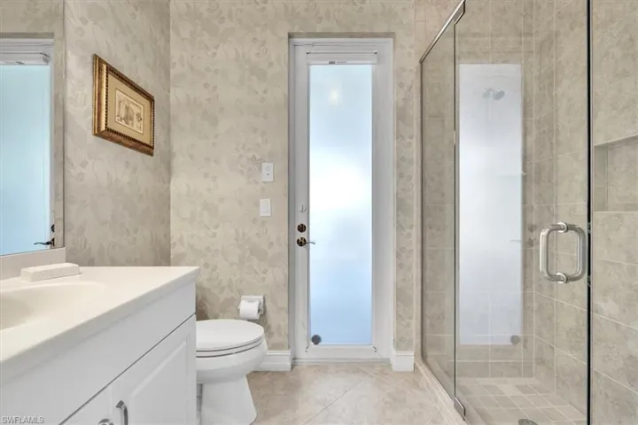 Bathroom with vanity, a stall shower, wallpapered walls, and light tile patterned floors