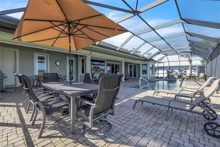 View of patio / terrace featuring glass enclosure, outdoor dining space, a sunroom, an outdoor pool, and a grill