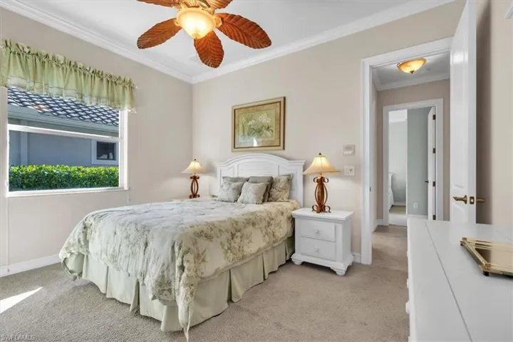 Bedroom with ornamental molding, light carpet, and a ceiling fan