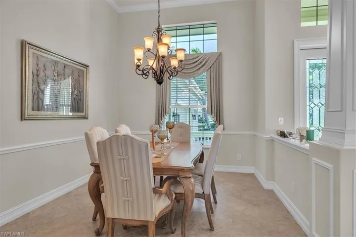 Dining room with ornamental molding, a chandelier, and light tile patterned floors