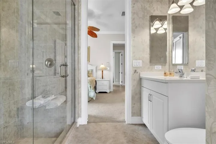 Bathroom featuring vanity, connected bathroom, wallpapered walls, light tile patterned floors, and a shower stall