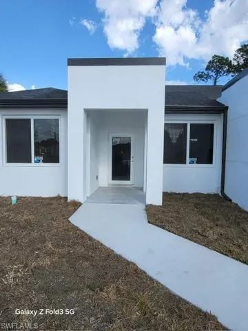 Property entrance with stucco siding and a shingled roof