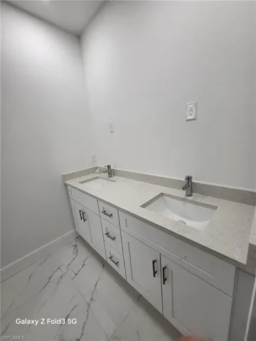 Bathroom featuring double vanity and light marble finish flooring