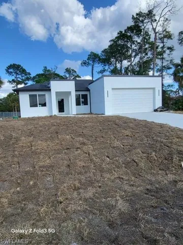 View of front of property with stucco siding, an attached garage, and driveway